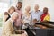 Group Of Seniors Standing By Piano And Singing Together