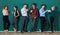 Group of six businesspeople colleague in modern company standing together in a row in front of the green wall and holding coffee