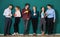 Group of six businesspeople colleague in modern company standing together in a row in front of the green wall and holding coffee