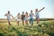 Group of six friends running down meadow, jumping, cheering and smiling. Friends having fun