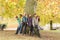 Group Of Six Teenage Friends Leaning Against Tree