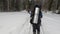 A group of skiers with big backpacks are skiing in a beautiful winter forest. First-person view. View from the back.