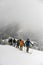 Group of skiers hiking on skis in snow up to the top of a snowy mountain slope. Skitour concept.