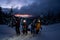 Group of skiers on snowy mountain against the background of snow-covered fir trees and evening sky