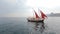 Group of slender models in bikinis relaxing on the luxury yacht with red sails in the open sea