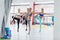 Group of slim Caucasian girls standing in one-leg stance during workout class in gym