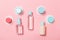 Group of small bottles for travelling on pink background. Copy space for your ideas. Flat lay composition of cosmetic products.