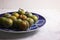 Group of small greengage plums on a blue plate, on white marble surface