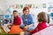 Group of small school kids with teacher sitting on bean bags in class, talking.