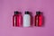 Group of small travel bottles for body care: shower gel, shampoo, balm, lotion on pink background.