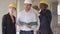 Group of smiling builders in hardhats with clipboard and blueprint outdoors