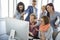 Group of smiling businesspeople using computer together in office