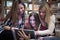 Group of smiling female students looking at tablet in library