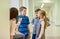 Group of smiling school kids talking in corridor