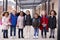 A group of smiling young multi-ethnic school kids wearing coats and carrying schoolbags standing in a row in walkway outside their