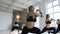 Group of sportive people in a gym training dressed in black body sports suits perform exercises for shaping breech and