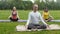 Group of sportsmen performs breathing exercise outdoors in a green park
