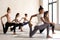 Group of sporty women practicing yoga, doing anjaneyasana exercise