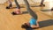 Group of sporty young women standing in pose with legs up during yoga workout in fitness studio