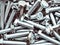 Group of stacked Industrial strong steel  bolts , zinc heap chrome. Dark industrial seamless high contrast background
