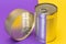 A Group of Stacked Tin Cans with Blank Edges on Split Yellow and Violet Background