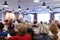 Group of students and journalists in the audience listens to the speaker in front of the projector and the screen.