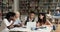 Group of students sit in library with laptop writing essay