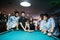 Group of stylish asian friends wear on jeans playing pool billiard on bar