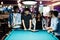 Group of stylish asian friends wear on jeans playing pool billiard on bar