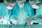Group of surgeons in masks performing operation. Scene of operation room colored in green. Medicine, surgery and