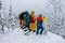 Group team of free-riders skiers, snowboarders stand on the mountainside and look down