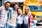 group of teen happy scholars looking at camera and embracing while standing in front of