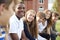 Group Of Teenage Students Sitting Outside School Buildings