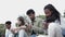 Group of teenage students using smart phones while sitting together outdoors