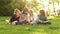 A group of teenagers sitting on the grass during a school break. Four children, boys and girls watch and discuss the