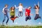 Group of teens jumping in the blue sky above the green grass