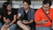 Group of teens sit on bench and use their smart phones