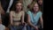 Group of teens, young people, friends sitting and standing around the TV and cheering, encouraging two girls who are