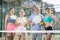 A group of tennis players posing next to the net holding Padel rackets