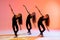 group of three ballet girls in black tight-fitting suits dancing on red background with their long hair down