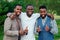 A group of three black men in stylish suits a meeting in a summer park. African-Americans friends hispanic businessman