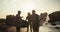 A group of three guys, surfer friends, stand, hold their surfboards and communicate against the background of the