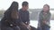 Group of three happy Asian teenagers sitting on the street at sunset time.