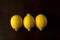 Group of three lemons in a row on dark background