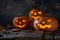 A group of three pumpkins and fallen dry leaves on wooden table.