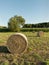 Group of three round bales of hay harvested in a field.