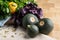 A group of three round green and yellow zucchinis on a wooden background. A bunch of fresh, raw parsley and basil.