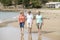 Group of three senior mature retired women on their 60s having fun enjoying together happy walking on the beach smiling playful