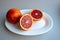 Group of three whole fresh orange mandarine on white ceramic plate isolated on gray background