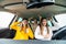 Group of three women having fun in the car. Women friends singing songs and dancing in car during road trip